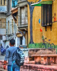 Rear view of man walking on street against building