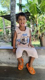 Portrait of young woman sitting on footpath