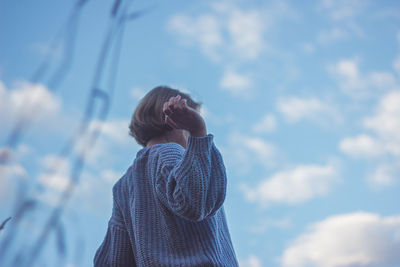 Low angle portrait of woman standing against sky