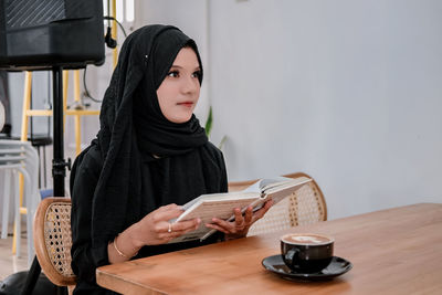 Portrait of young woman reading book
