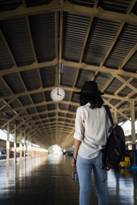 Rear view of woman standing at railroad station