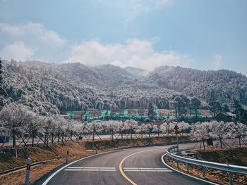 Road leading towards mountains against sky