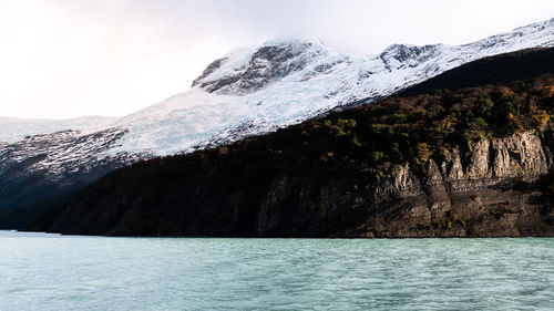 Scenic view of sea and snowcapped mountains against sky