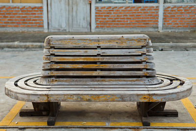 Empty bench on sidewalk by street in city