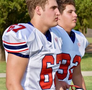 Thoughtful teenage boys wearing rugby uniforms while standing outdoors