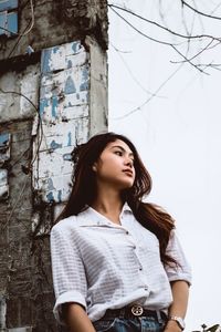 Beautiful young woman looking away against wall