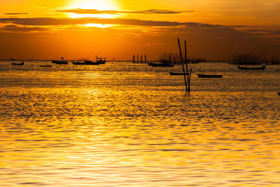 Silhouette sailboats in sea against sky during sunset