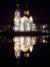 Illuminated building by lake at night
