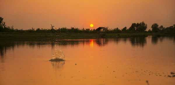 Scenic view of lake against orange sky