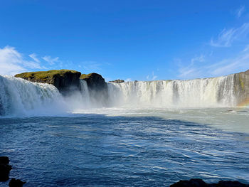 Scenic view of waterfall against clear blue sky