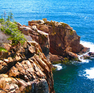 Rock formation by sea against sky