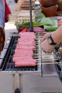 Midsection of person preparing food on barbecue grill