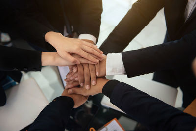 High angle view of cropped hands of business people stacking hands in office