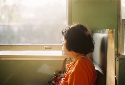 Side view of woman looking through train window