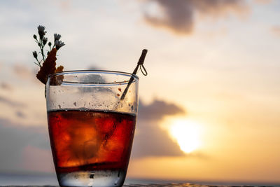 Close-up of drink on table against sky during sunset