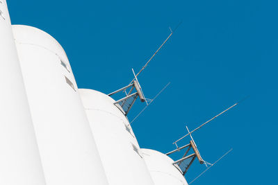 Low angle view of antennas on building against clear blue sky