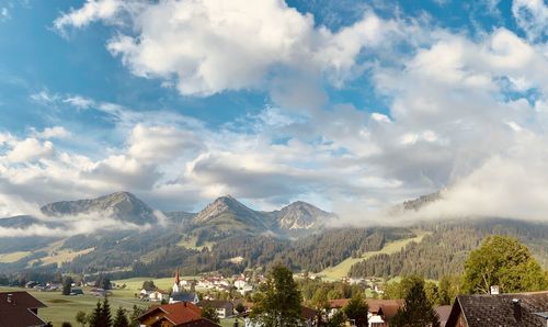 Panoramic shot of townscape against mountains surrounded by early morning fog