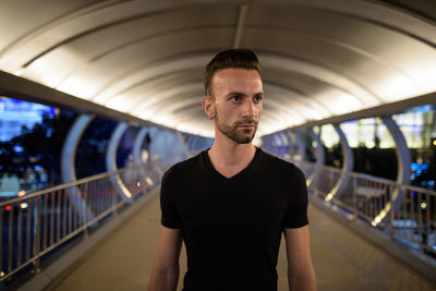 Young man standing against illuminated bridge