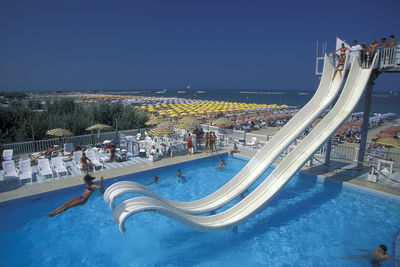 Panoramic view of swimming pool by sea against clear blue sky