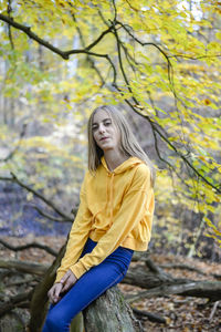 Portrait of smiling girl sitting on tree trunk in forest