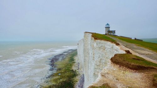 Lighthouse by sea against sky