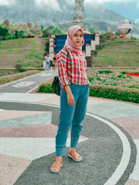 Portrait of young woman standing on road