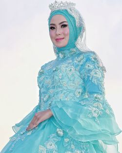 Portrait of smiling woman standing against blue sky