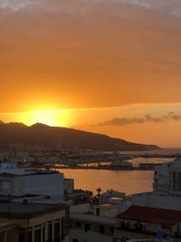 High angle view of harbor by buildings against sky during sunset