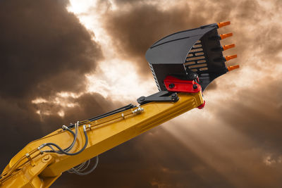 Excavator working on construction site with dramatic clouds on sky