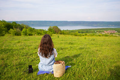 Rear view of woman standing on field against sky