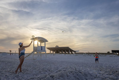 People at beach against sky during sunset