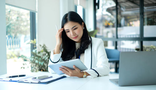 Young businesswoman using mobile phone at table