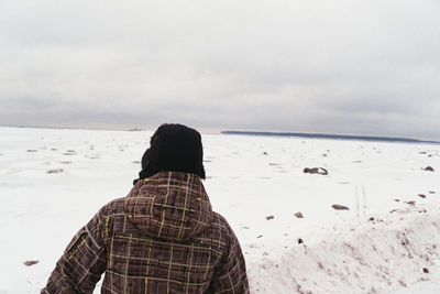 Rear view of man standing on beach against sky