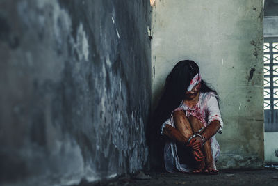 Woman sitting on wall of building