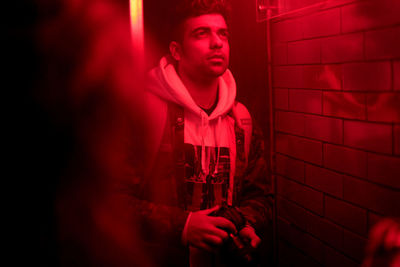 Portrait of young man standing against red wall