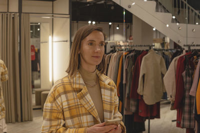 Woman trying on a coat in a fitting room of a clothing store