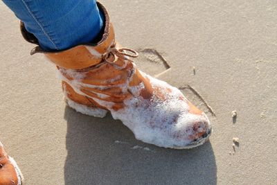 Low section of man shoes with surf at beach