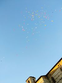 Low angle view of balloons flying against clear blue sky