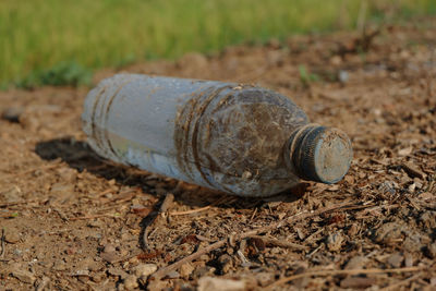 Close-up of abandoned bottle on field