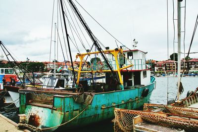 Boats moored at harbor against sky