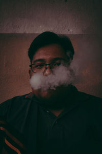 Portrait of young man smoking against wall