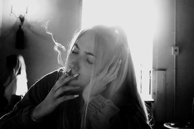 Portrait of young woman smoking cigarette at home