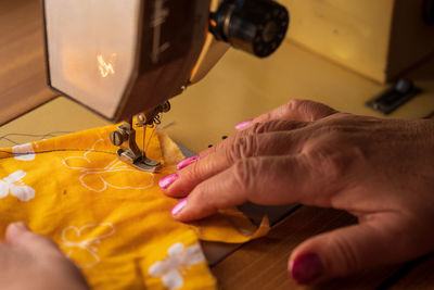 Midsection of woman using sewing machine on table