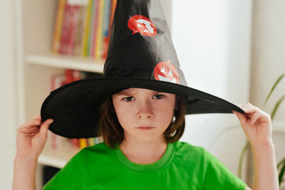 Portrait of a gloomy and creepy girl in a carnival witch hat. halloween holiday