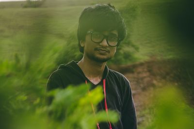 Portrait of young man wearing eyeglasses seen through plants