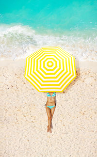 Low section of woman with umbrella on beach