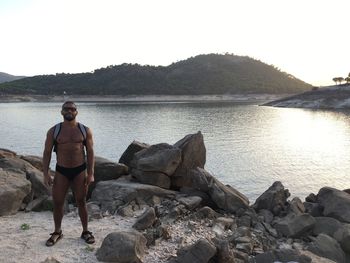 Full length of shirtless man standing by river