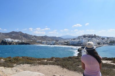 Rear view of woman standing on shore against sky