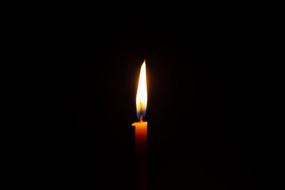 Close-up of lit candle in the dark