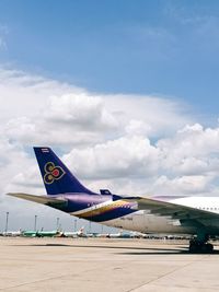 Airplane flying over airport runway against sky